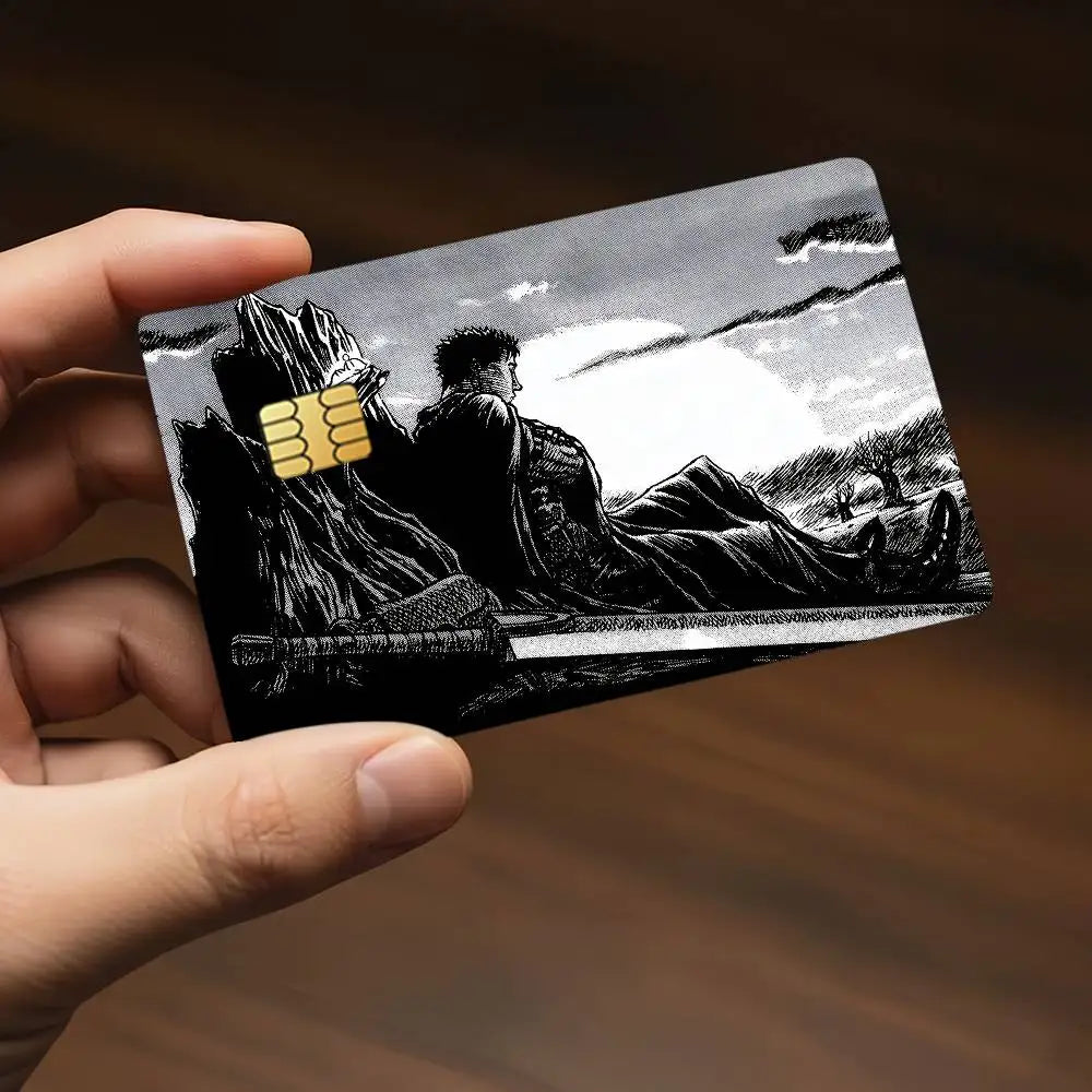 A hand holds a black and white illustration of a character from Berserk as an anime card sticker.
