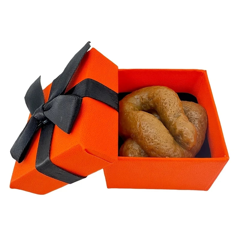 An orange box with a black ribbon holds a loaf of bread, a funny plastic prank toy.