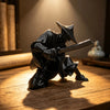 A dark 3D printed samurai warrior figurine in traditional attire wielding a sword, displayed on a wooden surface.