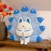 A white nine-tailed fox figure made of blue building blocks stands against a light background.