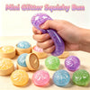 A hand holds a purple glitter squishy bun toy next to several other colorful squishy balls.