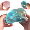 A hand holds a translucent blue squishy stress relief fidget toy and a pink ball.