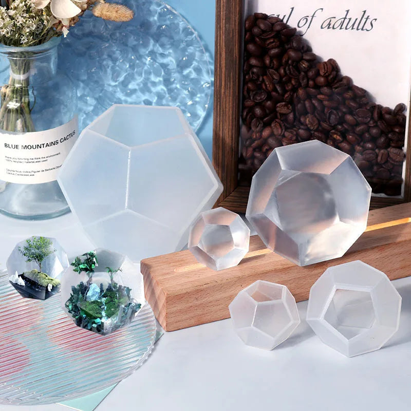 A collection of clear geometric resin casting molds and a jar of blue mountain cactus.