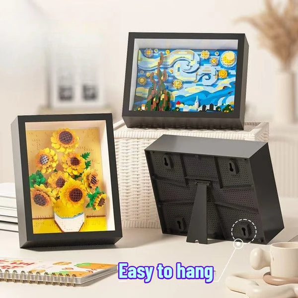 A black framed picture of a yellow sunflower, next to a black storage box and a white textured mat.