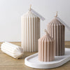Three cylindrical silicone candles in beige and pink tones with striped texture displayed on a white tray.