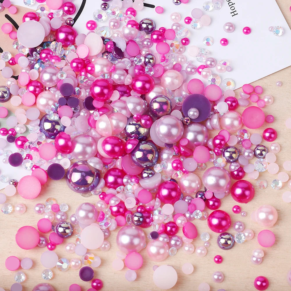 A scatter of mixed resin rhinestone pearls in various shades of pink and purple on a wooden surface.