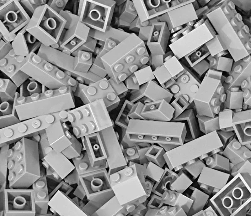 A close-up view of many gray plastic building blocks scattered randomly.