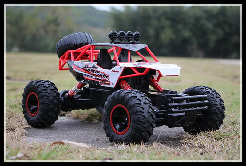 A red and black 4WD off-road monster truck with large tires and an LED headlight setup on a grassy field.