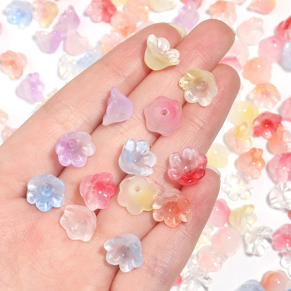 A hand holds a set of 50 glass beads shaped like cherry blossom flowers in various pastel colors.