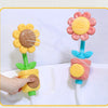 A hand is using a sunflower bath shower sprinkler toy for kids, which sprays water from a flower head.