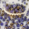 A pile of round, vibrant purple and gold beads for jewelry making