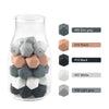 A clear glass jar filled with various hexagonal silicone beads in shades of gray, black, peach, and white.