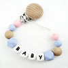 A beaded pacifier clip featuring wooden and silicone beads in pastel blue, pink, and natural wood tones.