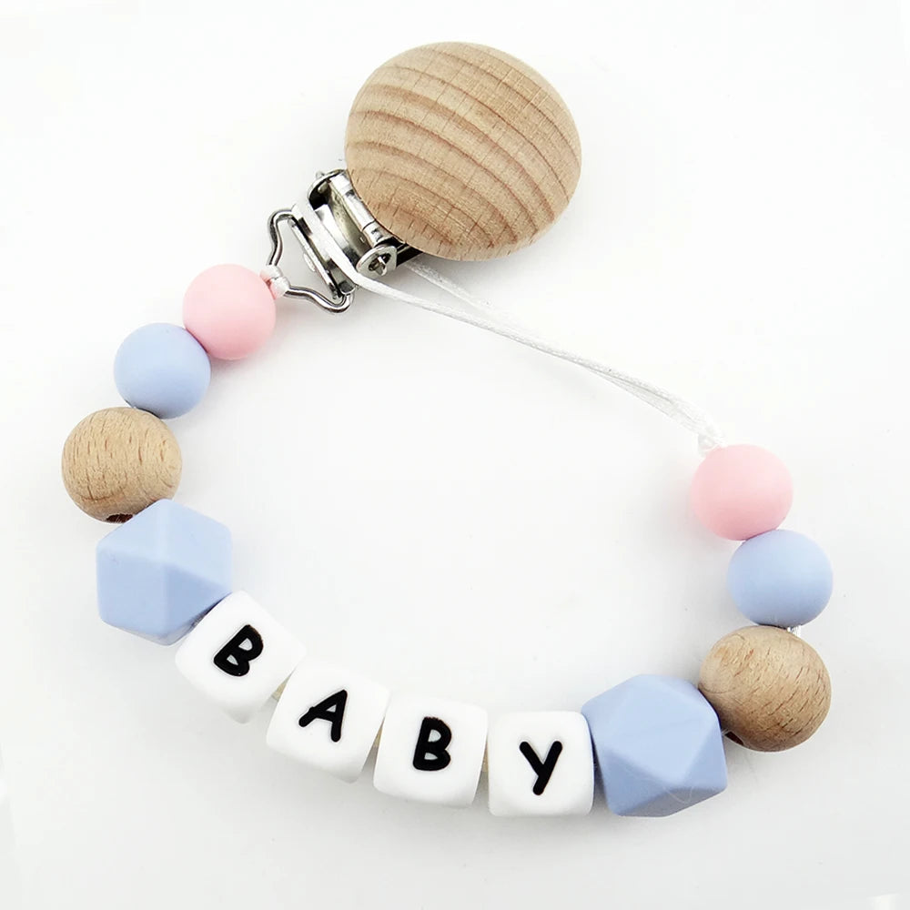 A beaded pacifier clip featuring wooden and silicone beads in pastel blue, pink, and natural wood tones.