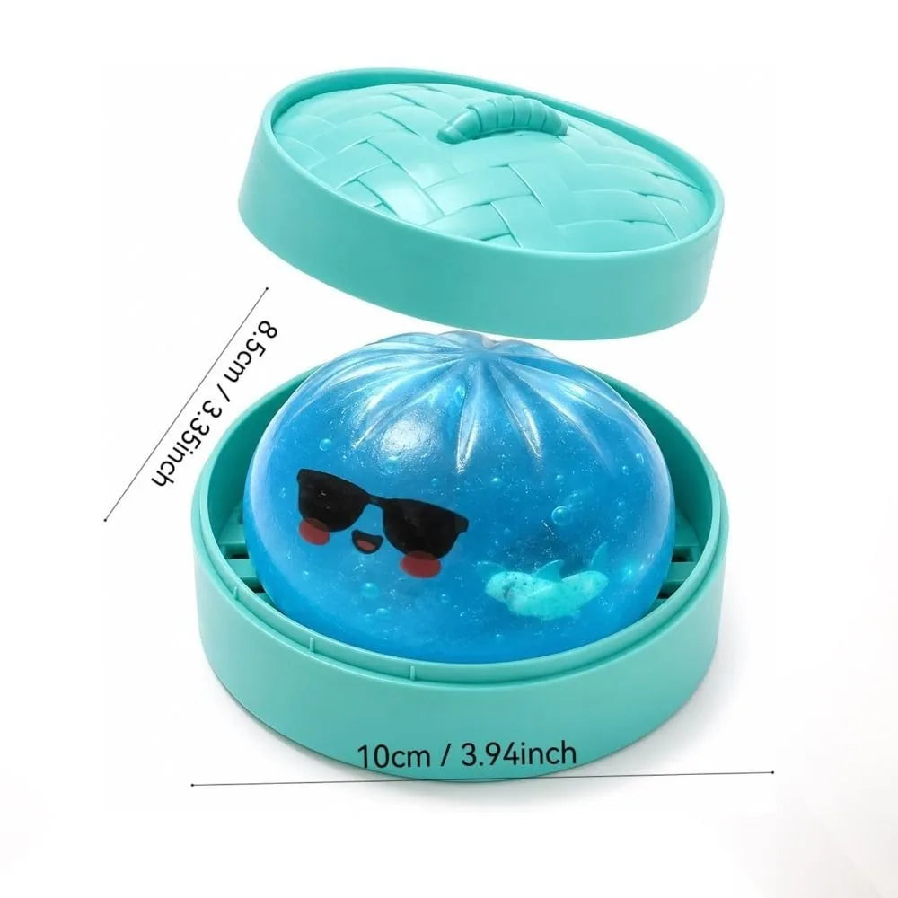 A blue glitter shark dumpling squishy fidget toy with a matching teal steamer box.