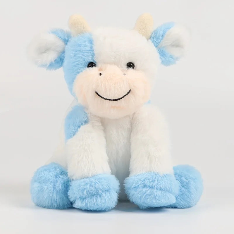 A white and light blue plush toy of a cow with floppy ears and a smiling face.