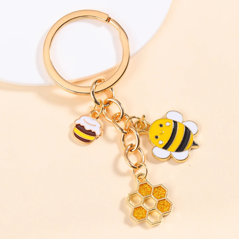 Gold-toned enamel flower keychain featuring a bee and a honeycomb design.