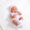 A lifelike vinyl reborn doll wearing a pink knitted outfit and matching hat, sitting on a white surface.