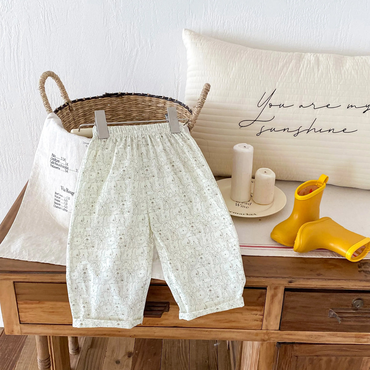 Cream plaid print casual pants with elastic waist laid out on a wooden surface.
