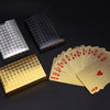 A collection of luxury gold foil playing cards and a black textured card are displayed on a dark surface.