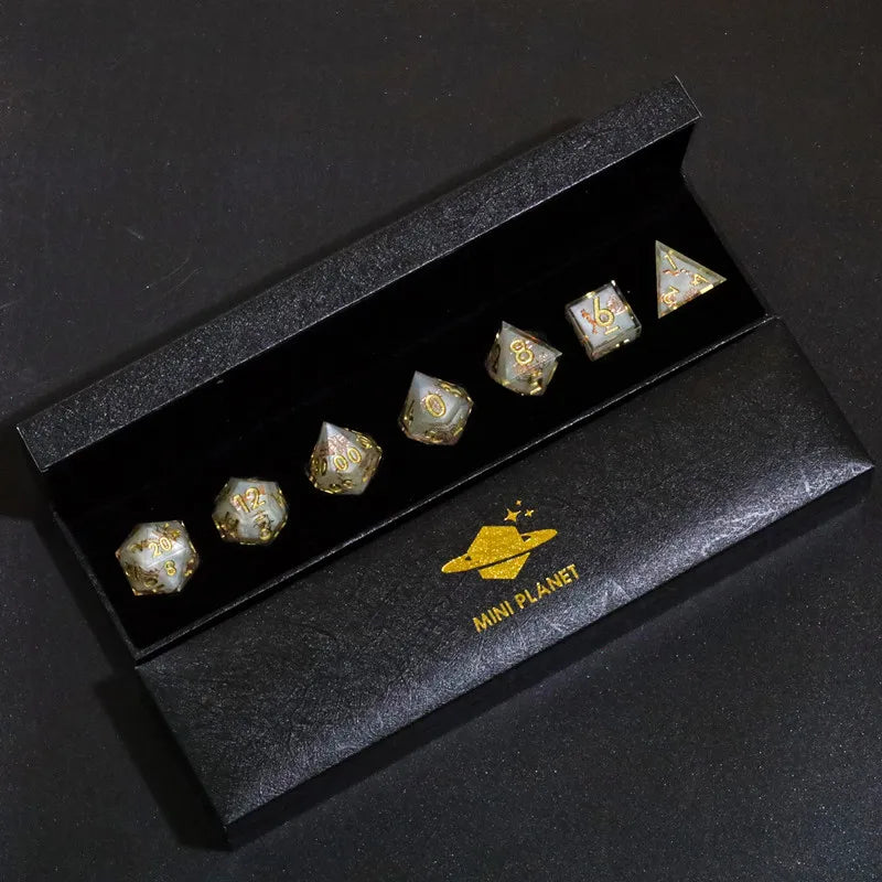 A set of mini planet polyhedral dice in a black box with gold accents.
