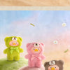 Three fluffy teddy bears in natural tones sit on pink and green mounds against a soft background.