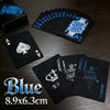 A set of blue playing cards and a joker card displayed on a dark wooden surface.