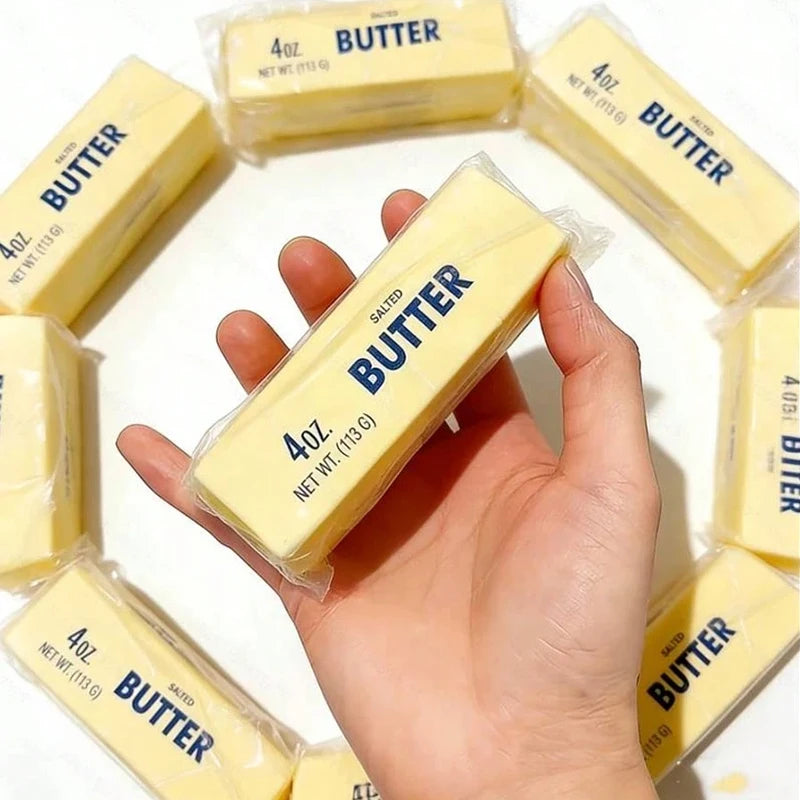 A hand holds a stick of salted butter, surrounded by other butter sticks.