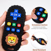 A hand holds a black lion-shaped silicone baby teether with remote control buttons, demonstrating its features.