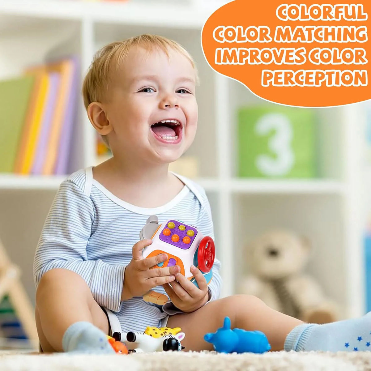 A smiling toddler holds a colorful Montessori sensory busy board cube toy.
