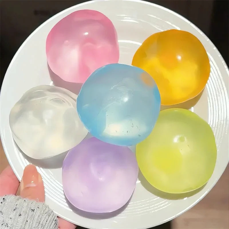 A collection of colorful, translucent silicone fidget balls in pink, blue, yellow, and green shades on a white plate.
