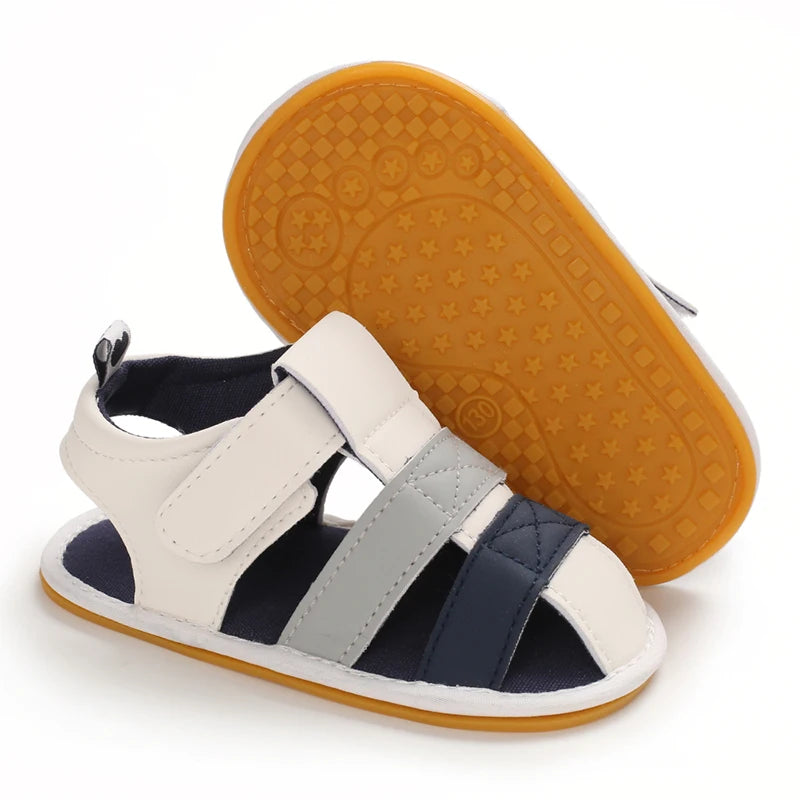A pair of white and navy breathable baby first walker sandals with an orange anti-slip sole.