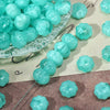 A collection of light blue translucent pumpkin-shaped resin beads for jewelry making displayed on a clear dish.