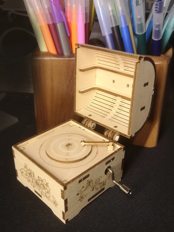 A wooden puzzle music box with an open lid and a smaller wooden box resting beside it.