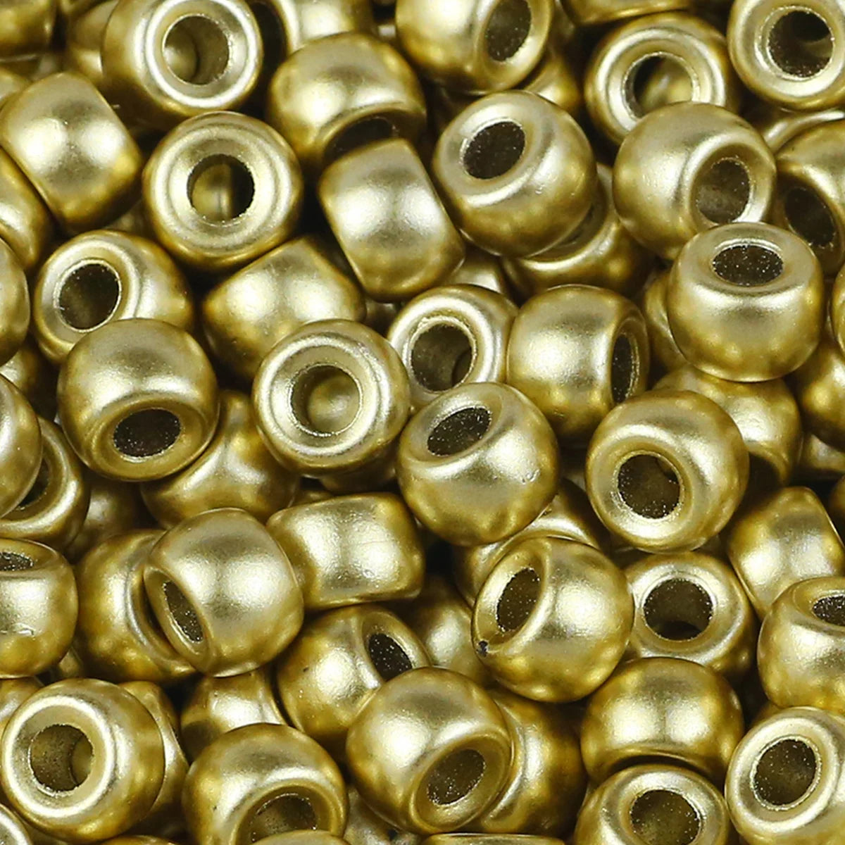 A close-up view of small, solid gold-colored pony beads for jewelry making and craft projects.