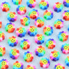 A collection of colorful polymer clay smiling sunflower beads scattered on a white surface.