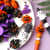 A collection of orange and black silicone beads shaped like pumpkins and bats for jewelry making.