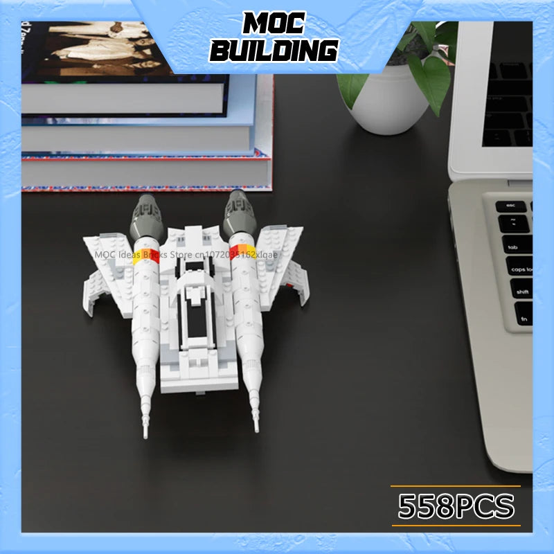 A white starfighter model kit with various components is displayed on a dark surface next to a laptop.