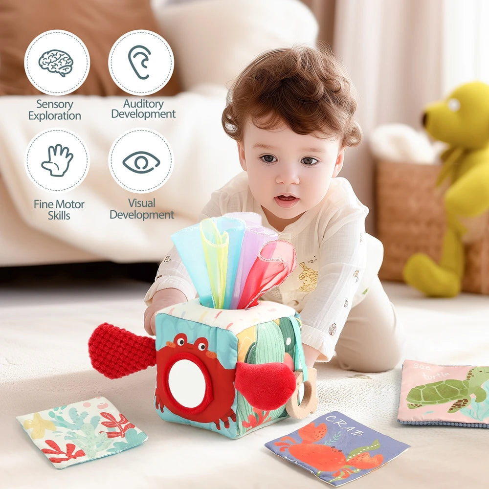 A baby is playing with a Montessori Magic Tissue Box toy featuring an ocean cloth book and various sensory developmental tool