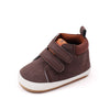 A pair of brown soft PU leather baby first walker shoes with an anti-slip TPR sole.
