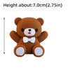 A small, round brown bear cake topper with white accents.