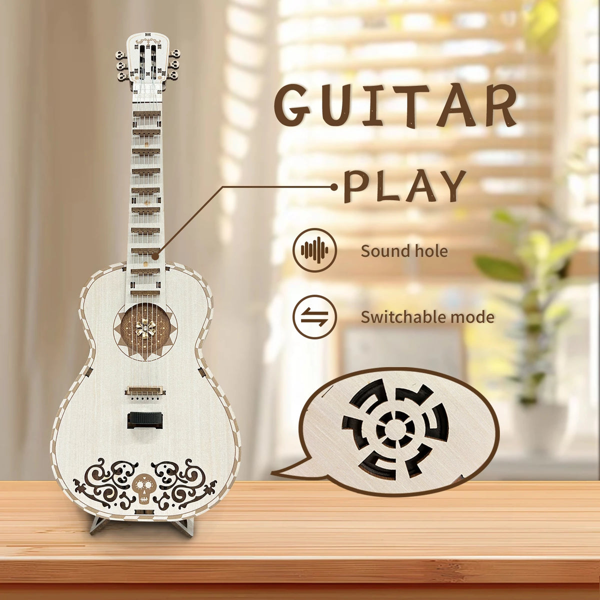 A light-colored wooden miniature guitar model kit with a sound hole and switchable mode feature displayed on a wooden surface
