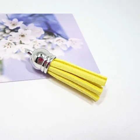 A bundle of bright yellow velvet tassels with silver metal findings displayed on a purple background.