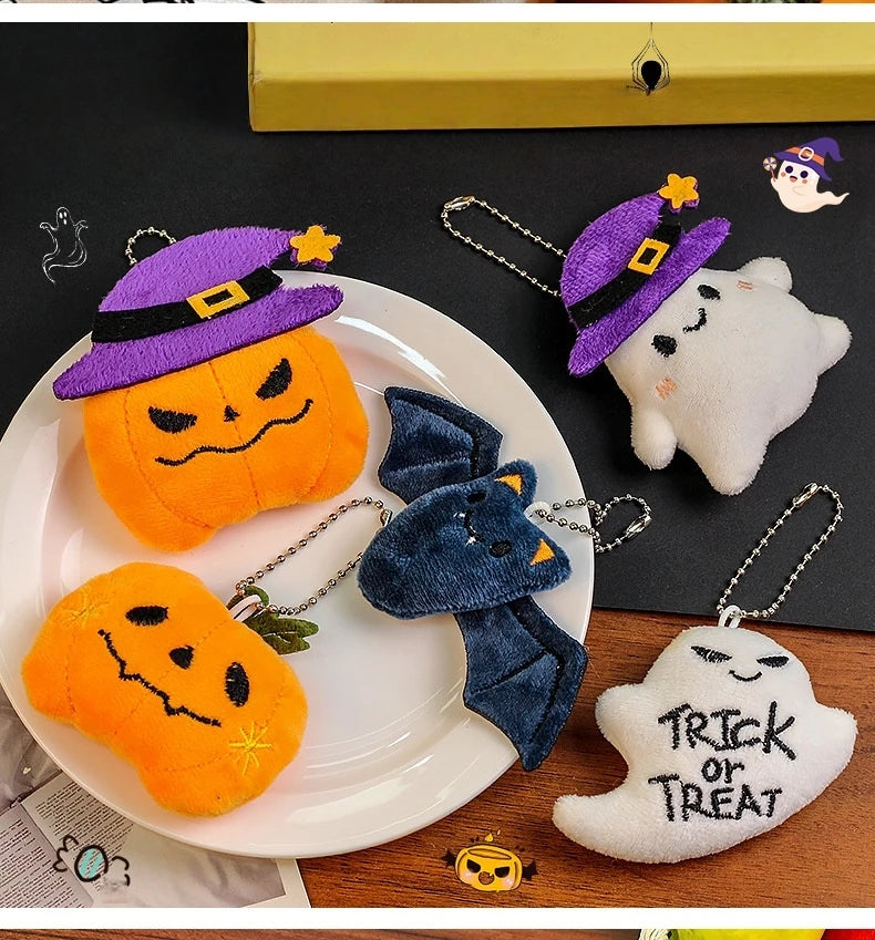 A set of Halloween plush keychains featuring a ghost, pumpkin, and bat charm on a white plate.