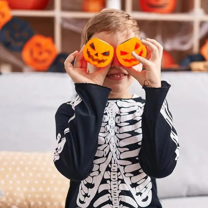 A young child is squeezing orange pumpkin and skeleton sensory toys over their eyes.