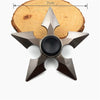 A metal fidget spinner with a star-like design and rainbow finish resting on a wooden surface.