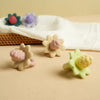 Silicone teething toys shaped like flowers and grapes in pastel colors resting on a beige surface.
