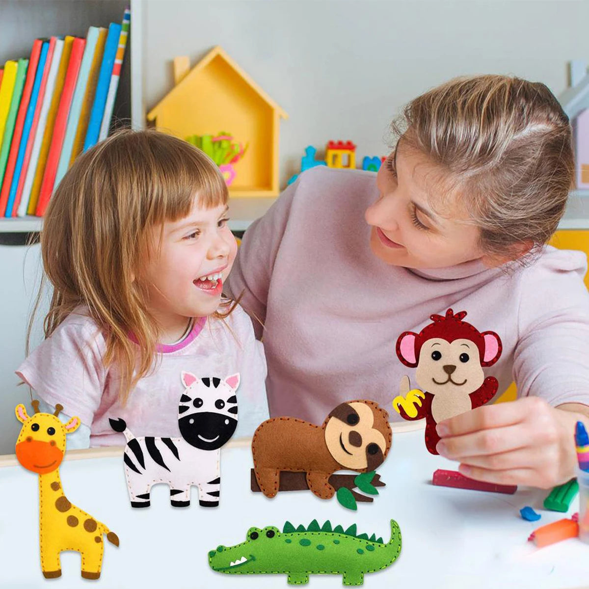 A girl and woman are looking at a felt sewing kit featuring various woodland animals like a giraffe, zebra, bear, and crocodi