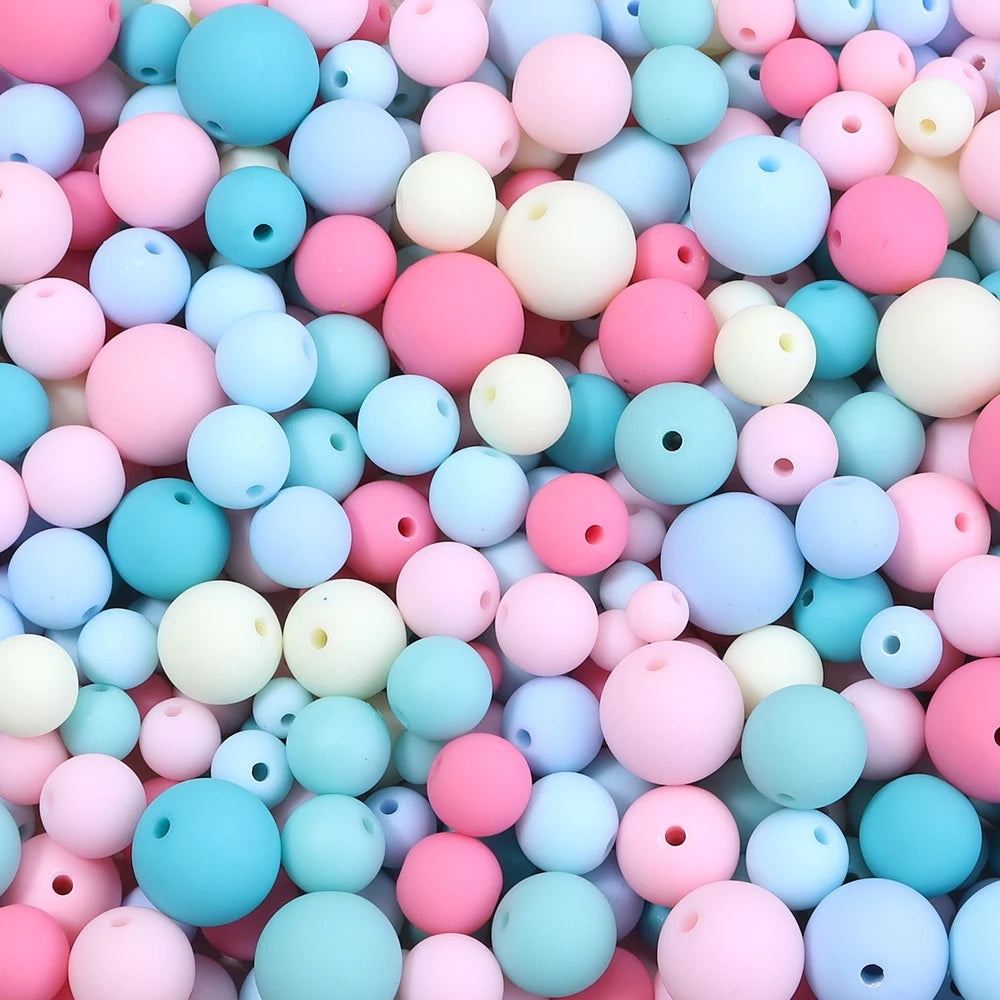 A close-up view of numerous matte acrylic beads in various shades of pink, blue, and white.