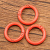 A set of ten bright orange metal O-ring spring clasps arranged in a triangle on a wooden surface.